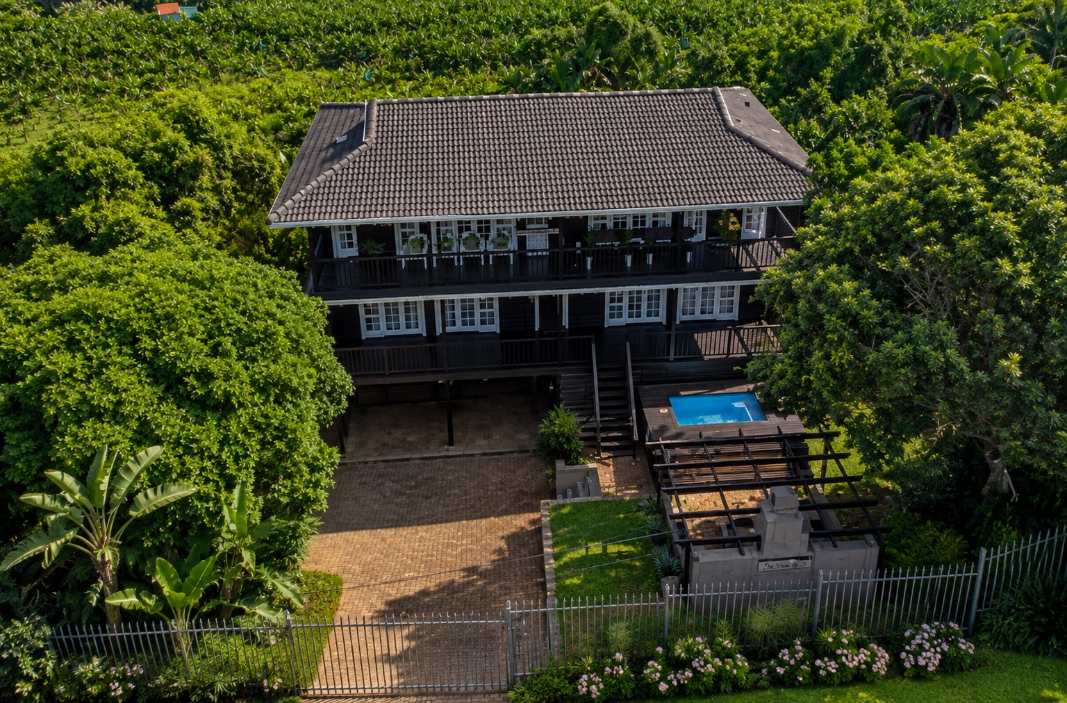 Aerial front view of the coastal home, pool and landscaped garden