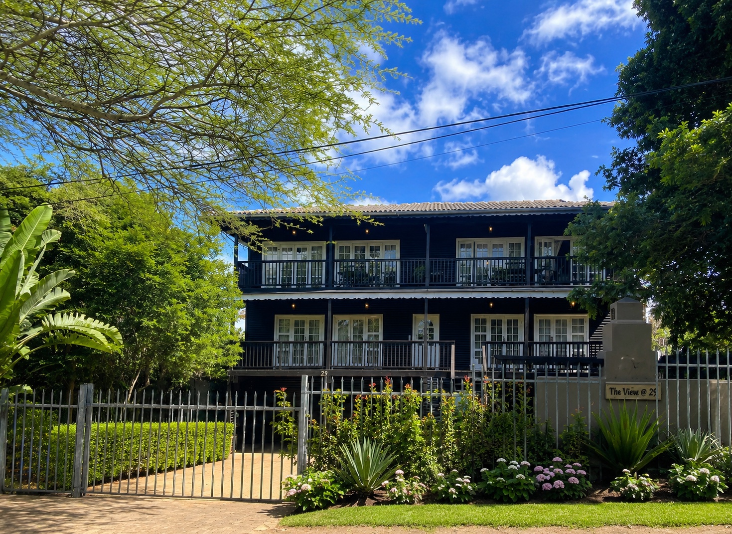 Front elevation of the home framed by mature tropical gardens