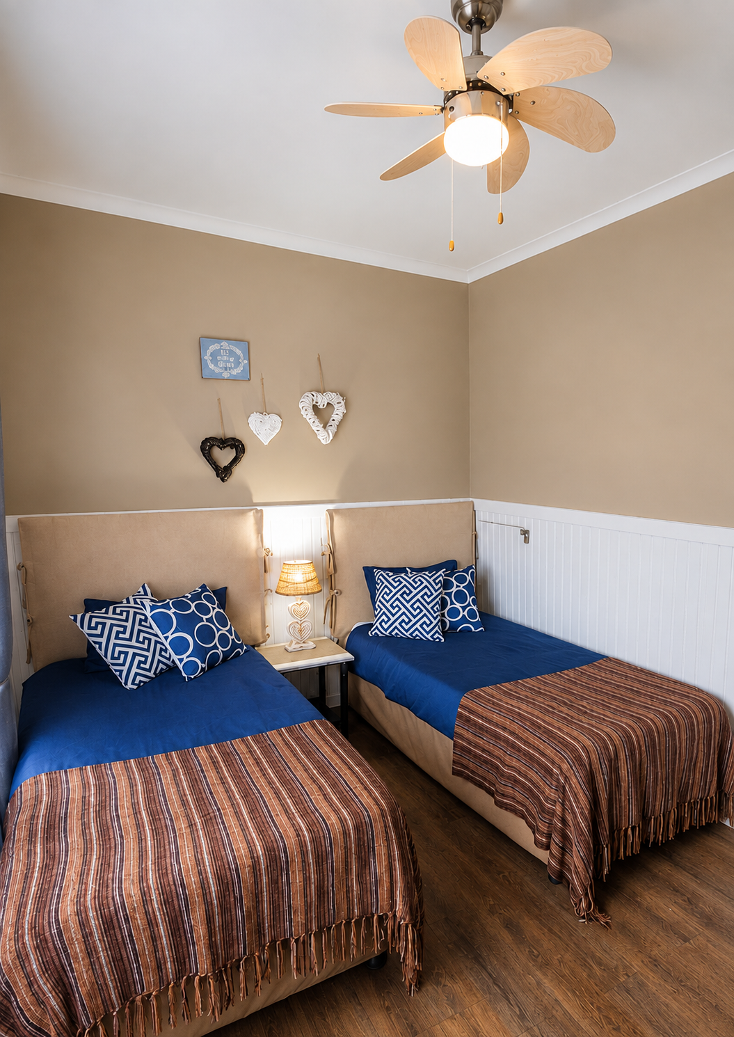 Twin bedroom with navy bedding and natural rattan bedside lamp